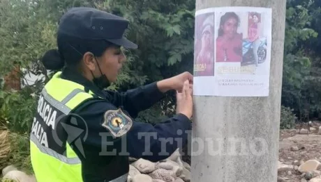 Policías ayudan a pegar afiches de búsqueda.