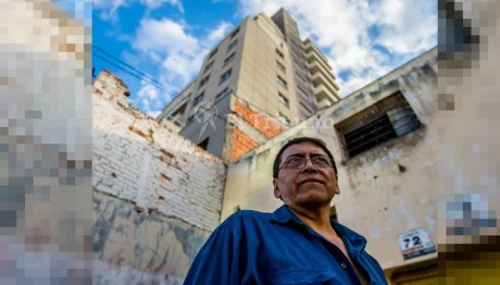 Ricardo Amador, frente a su dañada vivienda y con la torre que lo dejó en la calle a sus espaldas.