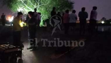 Los familiares del joven esperan en la orilla de la represa mientras la policía busca el cuerpo.